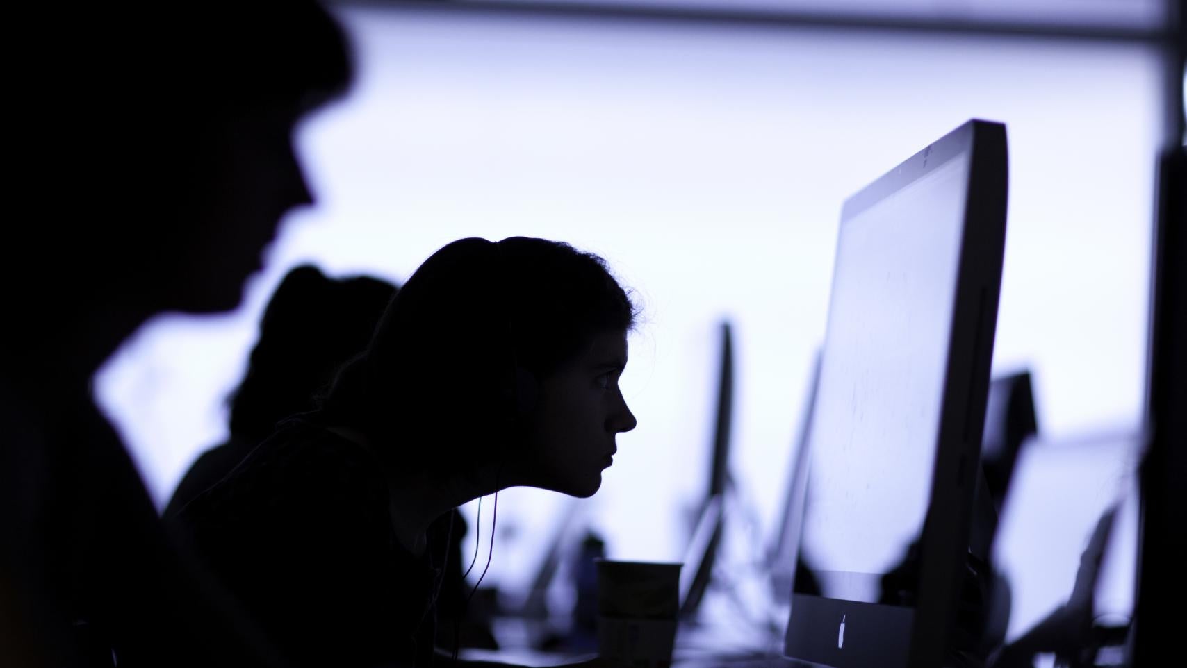 Student leaning into desktop screen.
