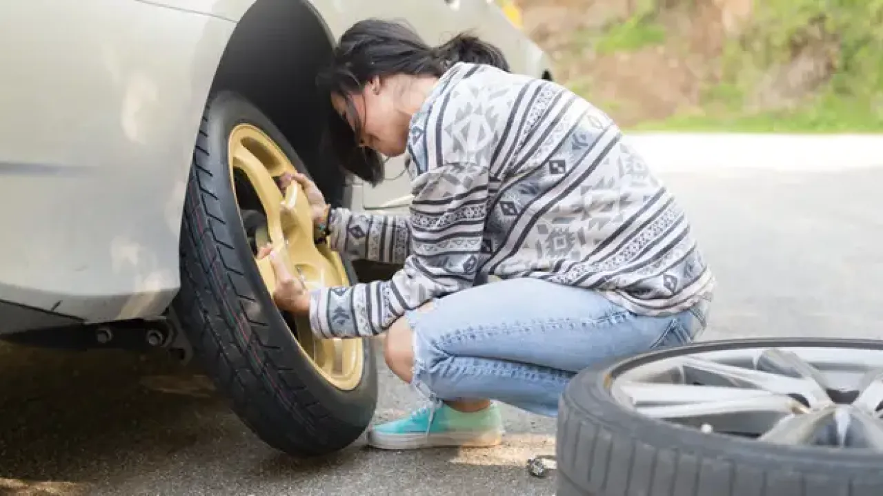 Woman changing a tire on the side of the street