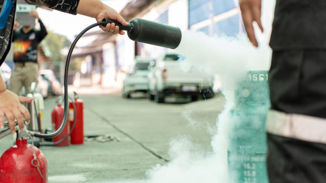 A bruin using a fire extinguisher at a fire safety event