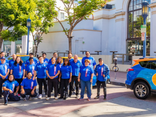 Employees of Primo Driving School, standing next to a branded car, posing as a group in Westwood Village